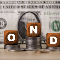 Bonds investment concept with letter blocks on coin stacks and US dollar banknote symbol of fixed income, interest rates, financial markets, portfolio diversification by following with FED strategy.