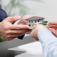 Hands passing a model family home during a property transfer in Andalucía.