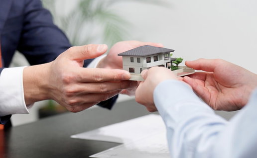 Hands passing a model family home during a property transfer in Andalucía.