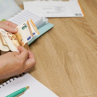 Person counting €50 banknotes beside financial paperwork, illustrating potential loan insurance refunds in Spain.
