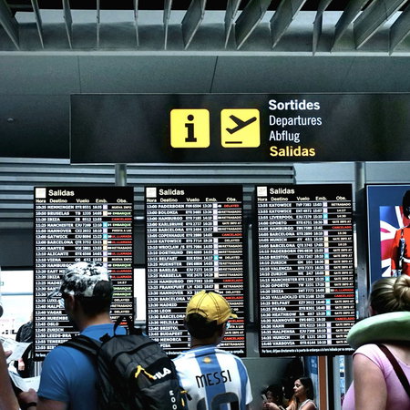 Travellers checking departure boards at a Spanish airport