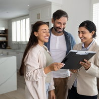 Couple reviewing property documents with a real estate professional in a modern home.