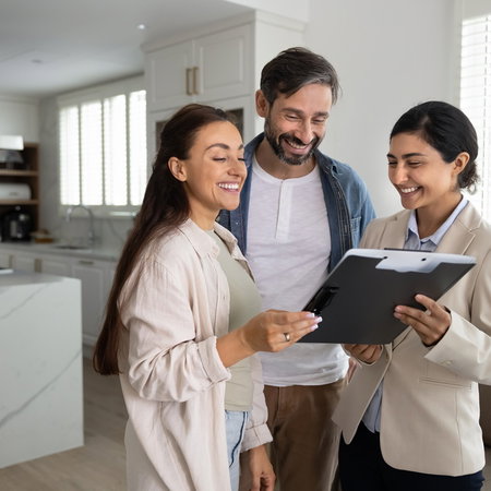 Couple reviewing property documents with a real estate professional in a modern home.