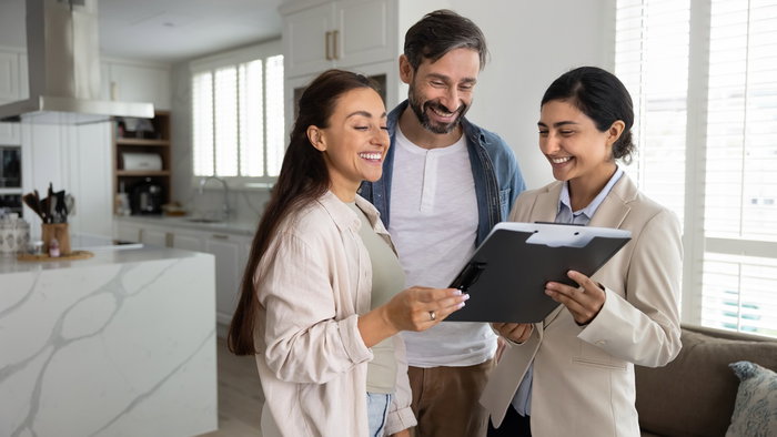 Couple reviewing property documents with a real estate professional in a modern home.