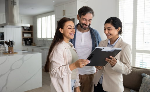 Couple reviewing property documents with a real estate professional in a modern home.