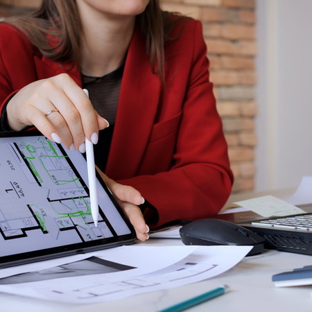 Property professional discussing an apartment floor plan displayed on a tablet.