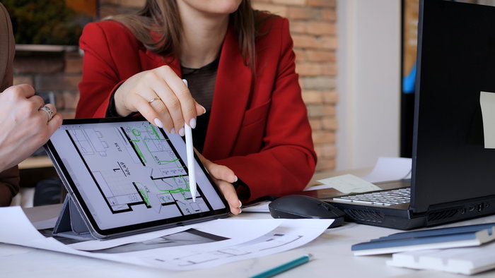 Property professional discussing an apartment floor plan displayed on a tablet.