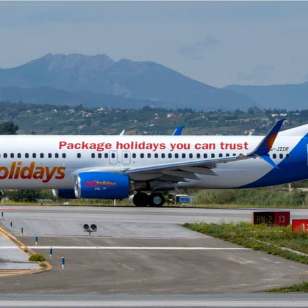 Jet2holidays aircraft on an airport taxiway with mountains in the background.