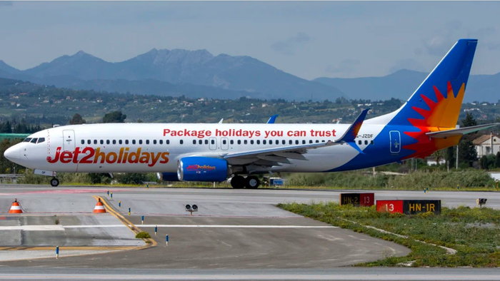 Jet2holidays aircraft on an airport taxiway with mountains in the background.