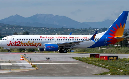 Jet2holidays aircraft on an airport taxiway with mountains in the background.