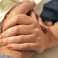 A patient holding a loved one's hand.