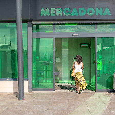 Woman entering a Mercadona supermarket in Spain as the retailer updates its food labels.