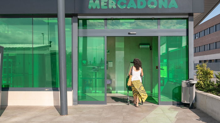 Woman entering a Mercadona supermarket in Spain as the retailer updates its food labels.