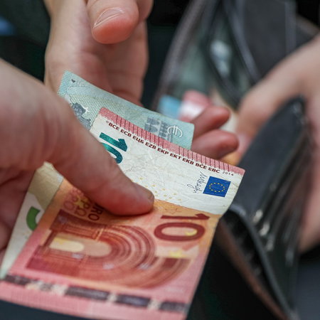 Person holding euro banknotes while another opens a wallet, illustrating Spain’s proposed minimum wage increase for 2027.