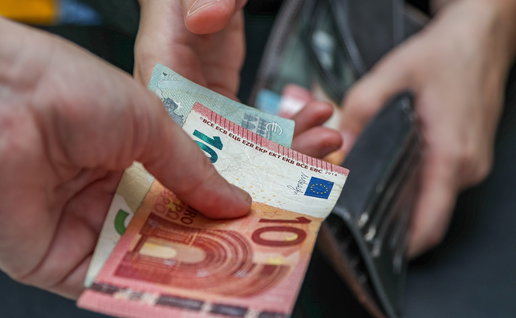 Person holding euro banknotes while another opens a wallet, illustrating Spain’s proposed minimum wage increase for 2027.