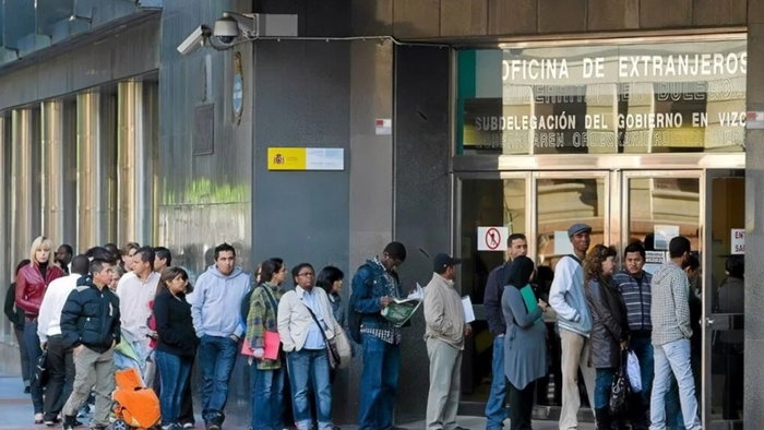 People queuing outside an immigration office in Spain to complete residency paperwork.