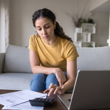Woman using a laptop to check her rental costs as Spain introduces new rent increase limits.