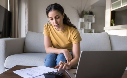 Woman using a laptop to check her rental costs as Spain introduces new rent increase limits.