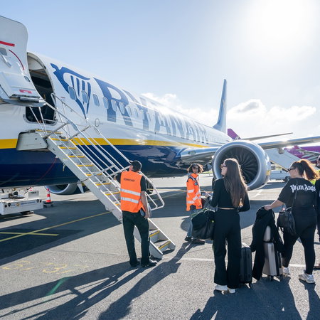 Passengers preparing to board a Ryanair aircraft at an airport.