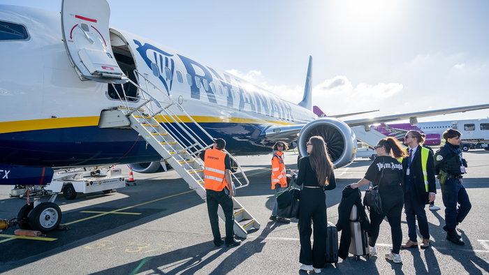 Passengers preparing to board a Ryanair aircraft at an airport.