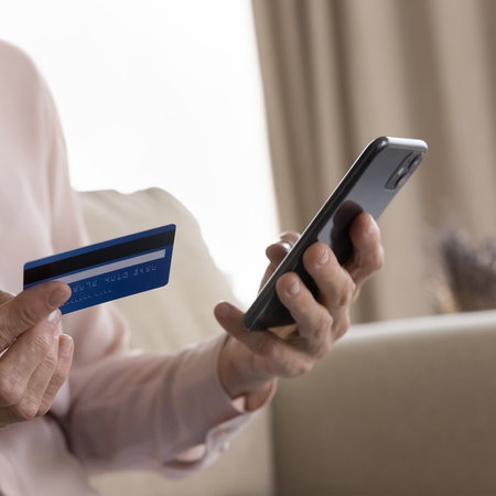Person holding a bank card and smartphone amid warnings of a phone scam in Spain