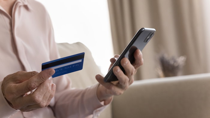 Person holding a bank card and smartphone amid warnings of a phone scam in Spain