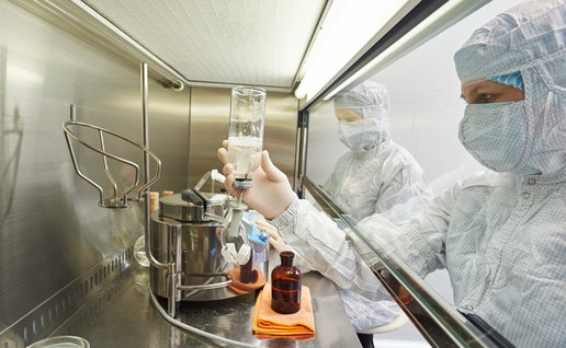 Lab workers in full scrubs managing biohazard material from a confined section of a lab