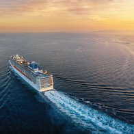 Aerial view of a cruise ship traveling over the ocean during a golden summer sunset with copy space