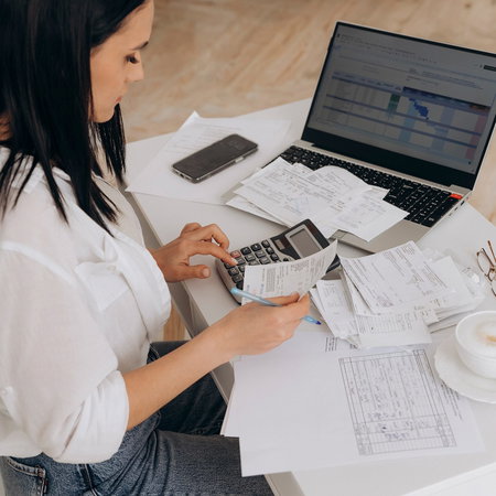 Side view of a woman doing expenses on a laptop