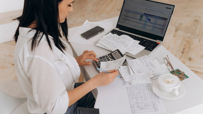 Side view of a woman doing expenses on a laptop