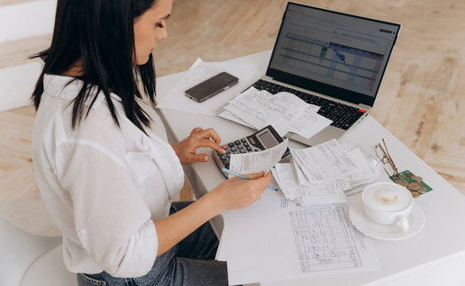 Side view of a woman doing expenses on a laptop