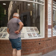 Man looking in estate agent window for rental properties