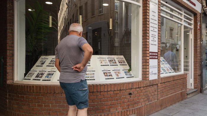 Man looking in estate agent window for rental properties