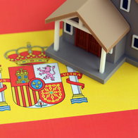 A model house on the Spanish flag, illustrating property ownership in Spain.