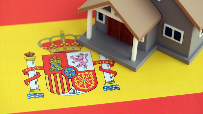 A model house on the Spanish flag, illustrating property ownership in Spain.