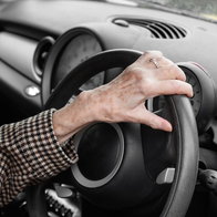 old person's hands on the steering wheel