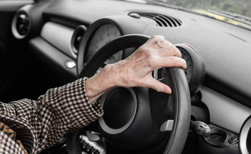 old person's hands on the steering wheel