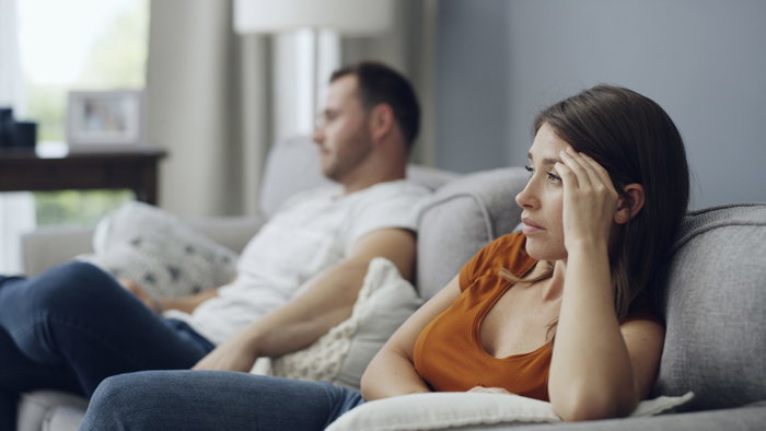 Couple sitting on a sofa not talking to each other after an argument