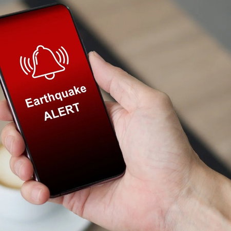 Smartphone displaying an earthquake alert message, illustrating Spain's updated earthquake risk and emergency planning rules.