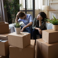 Worried couple sitting among moving boxes, illustrating the impact of eviction proceedings in Spain.