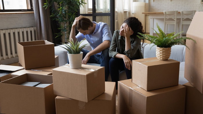 Worried couple sitting among moving boxes, illustrating the impact of eviction proceedings in Spain.
