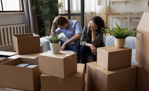Worried couple sitting among moving boxes, illustrating the impact of eviction proceedings in Spain.