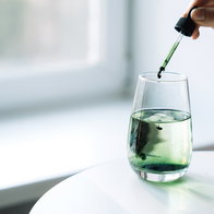 Dropper adding green liquid to a glass, illustrating Spain's recall of a supplement containing undeclared sildenafil.