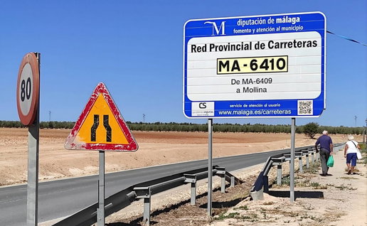 worn out road signs and elderly couple walking along the edge of the road