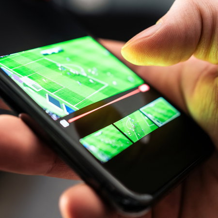 Person watching a live football match on a smartphone.
