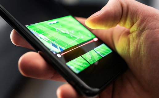Person watching a live football match on a smartphone.